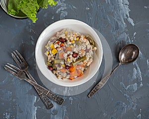 Perlotto with vegetables and pieces of fried pork, on a gray background