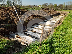 Permaculture trench construction with half long logs of wood