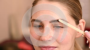 Permanent eyebrow styling. The master applies the composition for laminating the eyebrows with a wooden spatula.
