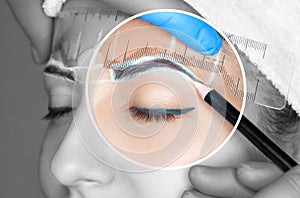 Permanent make-up for eyebrows of beautiful woman with thick brows in beauty salon. Closeup beautician doing tattooing eyebrow.