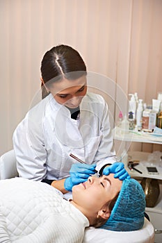 Permanent make-up wizard makes eyebrow correction procedure. Microblading