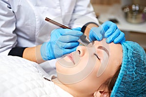 Permanent make-up wizard makes eyebrow correction procedure. Microblading