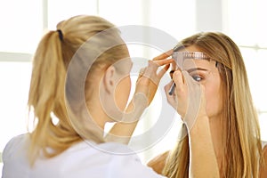 Permanent Makeup For Eyebrows. Beautiful Woman With Thick Brows In Beauty Salon. Beautician Doing Eyebrow Tattooing For