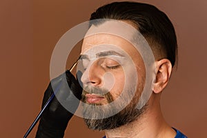 Tinting brows. Handsome man with eyebrows in barber shop. photo