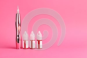 Permanent makeup machine and pigments on pink background. Space for text photo