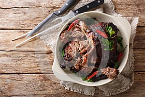 Pernil asado slow cooked shredded pulled pork close-up on a plate. horizontal top view