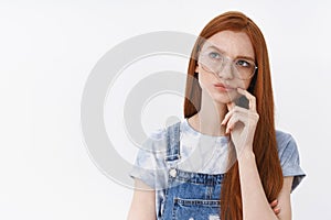 Perplexed attractive young redhead girl thinking solving puzzle in head, frowning touch lip thoughtful, pondering, look