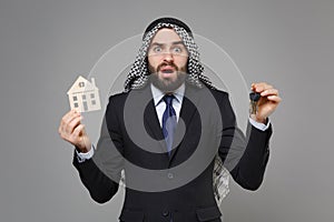 Perplexed bearded arabian muslim businessman in keffiyeh kafiya ring igal agal classic black suit tie isolated on gray