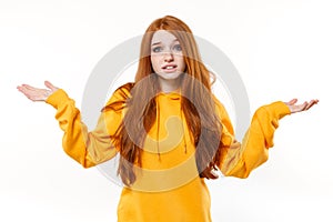 Perplexed displeased young redhead woman girl in casual yellow hoodie posing isolated on white wall background studio