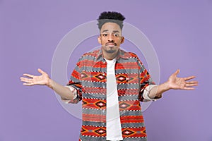 Perplexed dissatisfied young african american guy in casual colorful shirt posing isolated on violet background studio