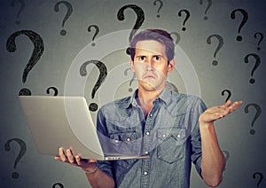 Perplexed man with laptop many questions and no answer