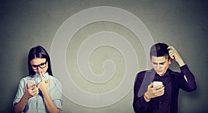 Perplexed man and woman looking at mobile phone