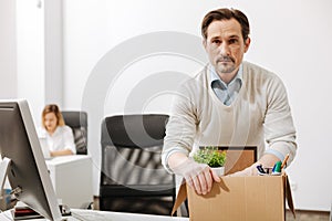 Perplexed manager holding the box and sitting in the office