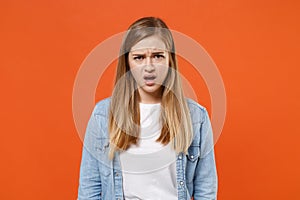 Perplexed shocked young woman girl in casual denim clothes posing isolated on orange wall background studio portrait