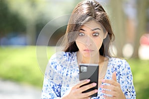 Perplexed woman checking phone in the street
