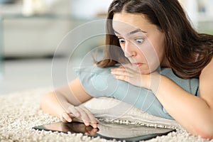 Perplexed woman using tablet at home