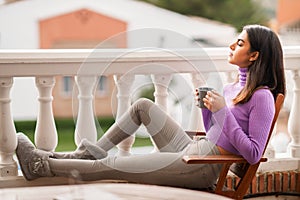 Persian woman on her balcony having a mug of coffee