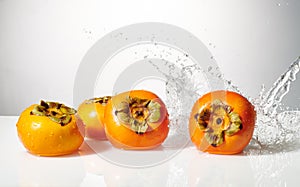 Persimmon fruit with water splash isolated on white.