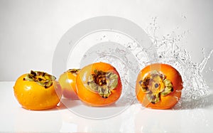 Persimmon fruit with water splash  on white.