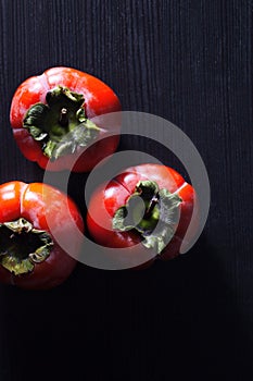 Persimmon fruit on wooden Board, black background.