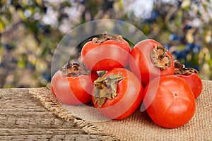 Persimmon fruit on wooden table with blurred garden background