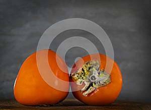 Persimmon. fruits isolated. Sweet exotic fruit at the table, dark background. Orange bowl, tropical fruits, autumn