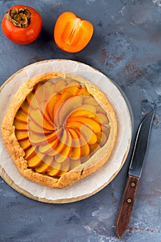 Persimmon galette, pie, tart on a gray stone background. Top view. Selective focus
