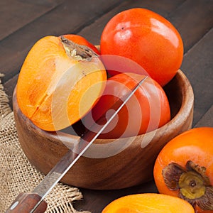 Persimmons in bowl with kitchen knife on table. photo