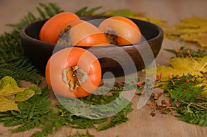 Persimmons on leaves over wooden background