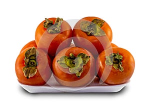Persimmons stacked on a white plastic plate isolated on a white background