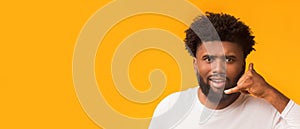 Persistent afro guy showing call me gesture over orange background