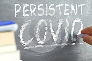 Persistent Covid concept. Hand writing on a blackboard. photo