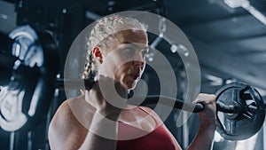 A Persistent Female Powerlifter Training by Lifting a Heavy Barbell in a Dark Gym. Portrait of a