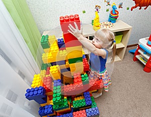 Persistent little girl building big block tower in daycare