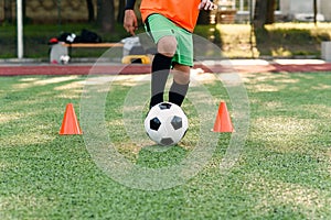 Persistent teen soccer player kicking ball on field. Close up feet of footballer kicking ball on green grass.