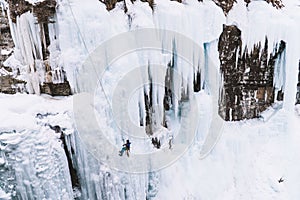 Person abseiling on a large frozen waterfall with huge icicles at Johnston Canyon, Banff