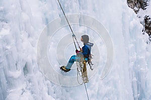 Person abseiling on a large frozen waterfall with huge icicles at Johnston Canyon, Banff