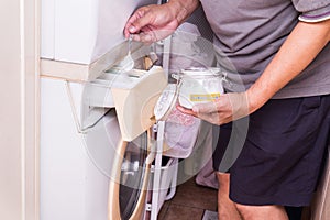 Person adding baking soda into washing machine to wash clothes