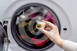 Person adding laundry detergent pod to the washer full with clothes.