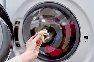 Person adding laundry detergent pod to the washer full with clothes