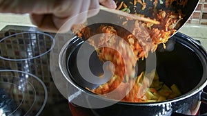 Person adds fried carrot in cooking pan