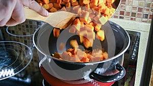 Person adds fried pumpkin in cooking pan