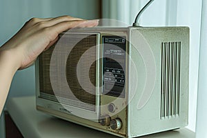 A person adjusting the knobs on an analog radio