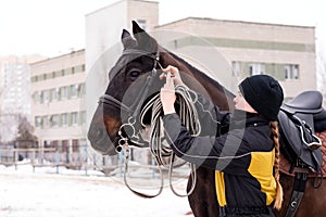 Person adjusting reins on saddled horse outdoors