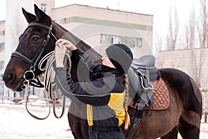 Person adjusting reins on saddled horse outdoors photo