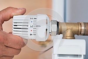 Person Adjusting Temperature Of Radiator Thermostat