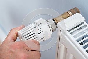 Person adjusting temperature of radiator thermostat