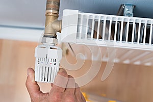 Person adjusting temperature of radiator thermostat
