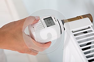 Person Adjusting Temperature On Thermostat