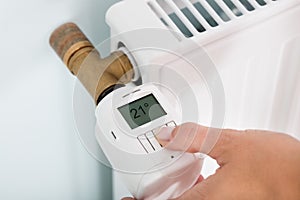 Person Adjusting Temperature On Thermostat